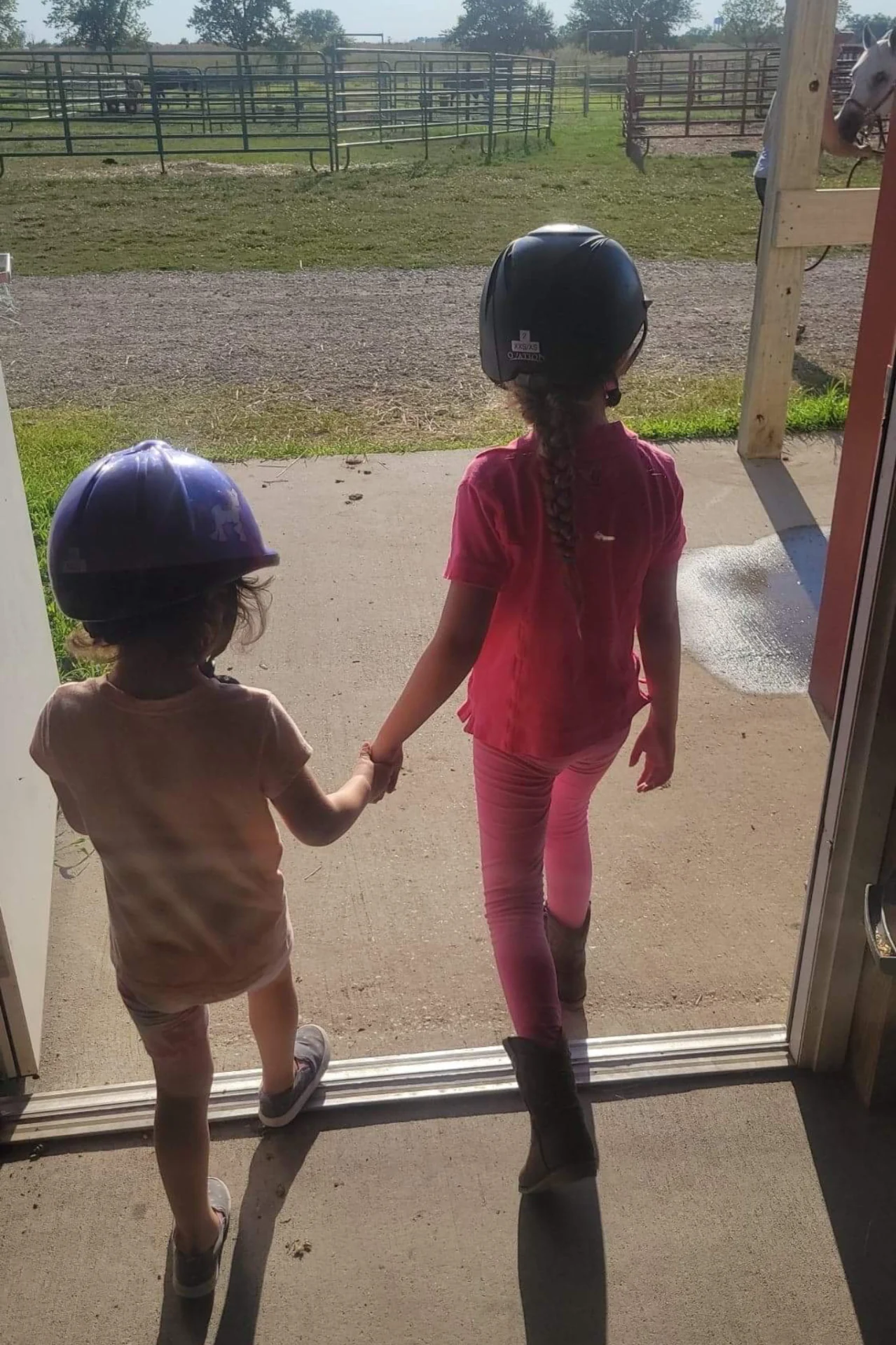 two young girls holding hands and wearing helmets