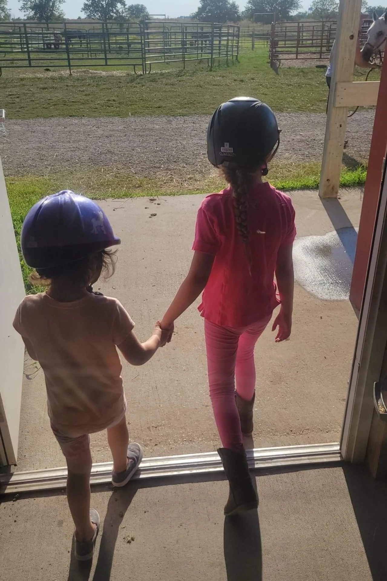 Two young girls holding hands while standing outside.