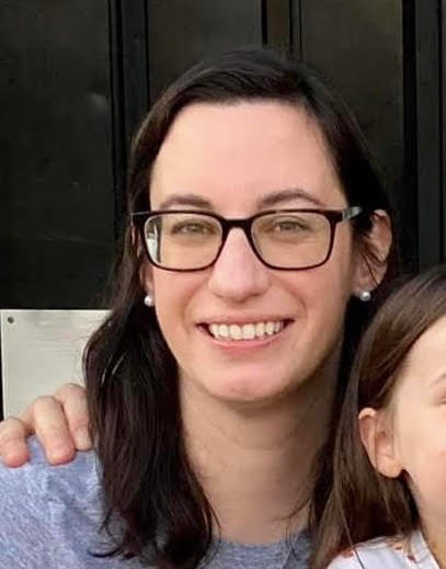 A woman with glasses and a smile on her face.