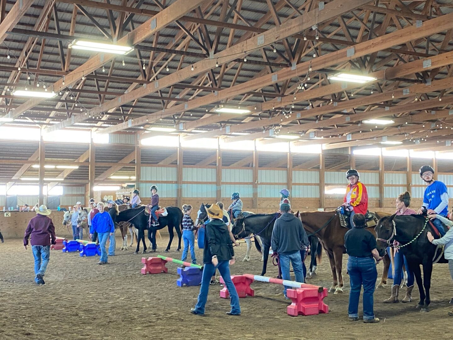 A group of people standing around horses in an arena.