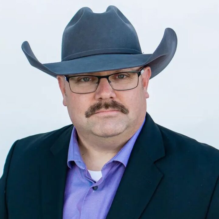 A man with a mustache wearing a hat and glasses.