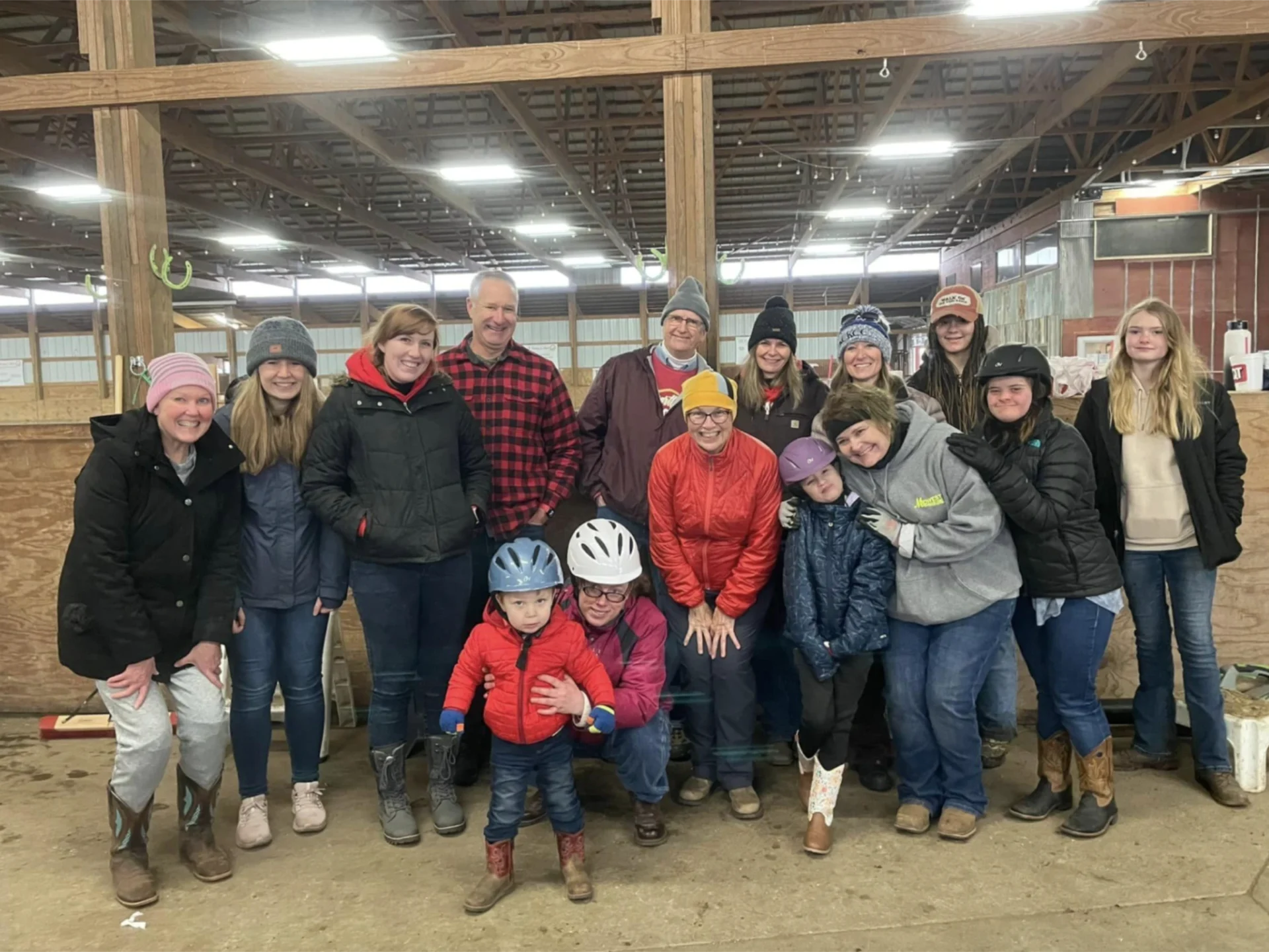 A group of people in the barn with helmets on.
