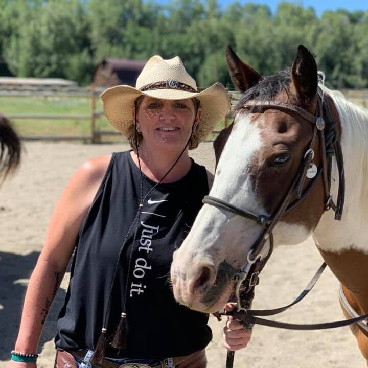 woman wearing a cowboy hat and standing with a horse